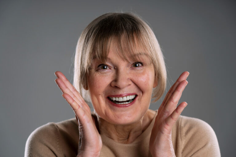 Mulher idosa sorrindo satisfeita com dentes alinhados após tratamento com coroa de porcelana ou zircônia na Clínica Adachi em Santo André.